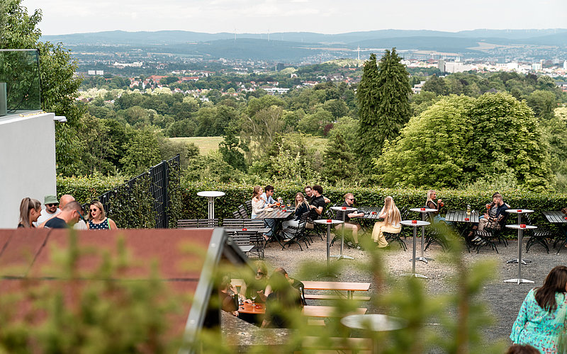 Blick auf Biergarten umringt von Bäumen