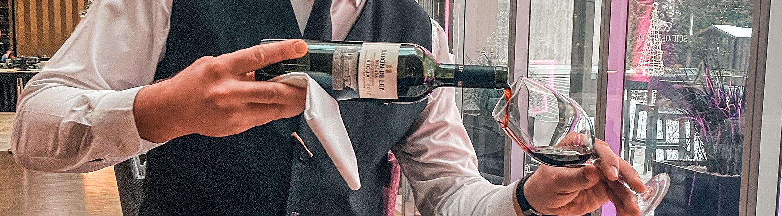Servicekraft schenkt Rotwein ein